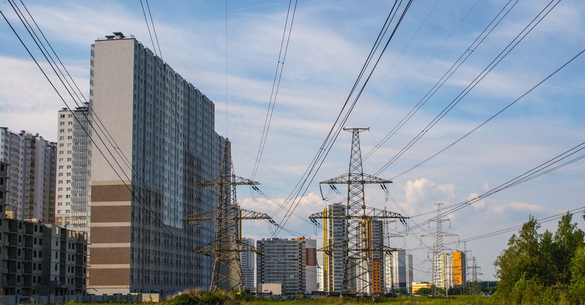 Urban scene showcasing apartment buildings and electricity towers under a clear sky.