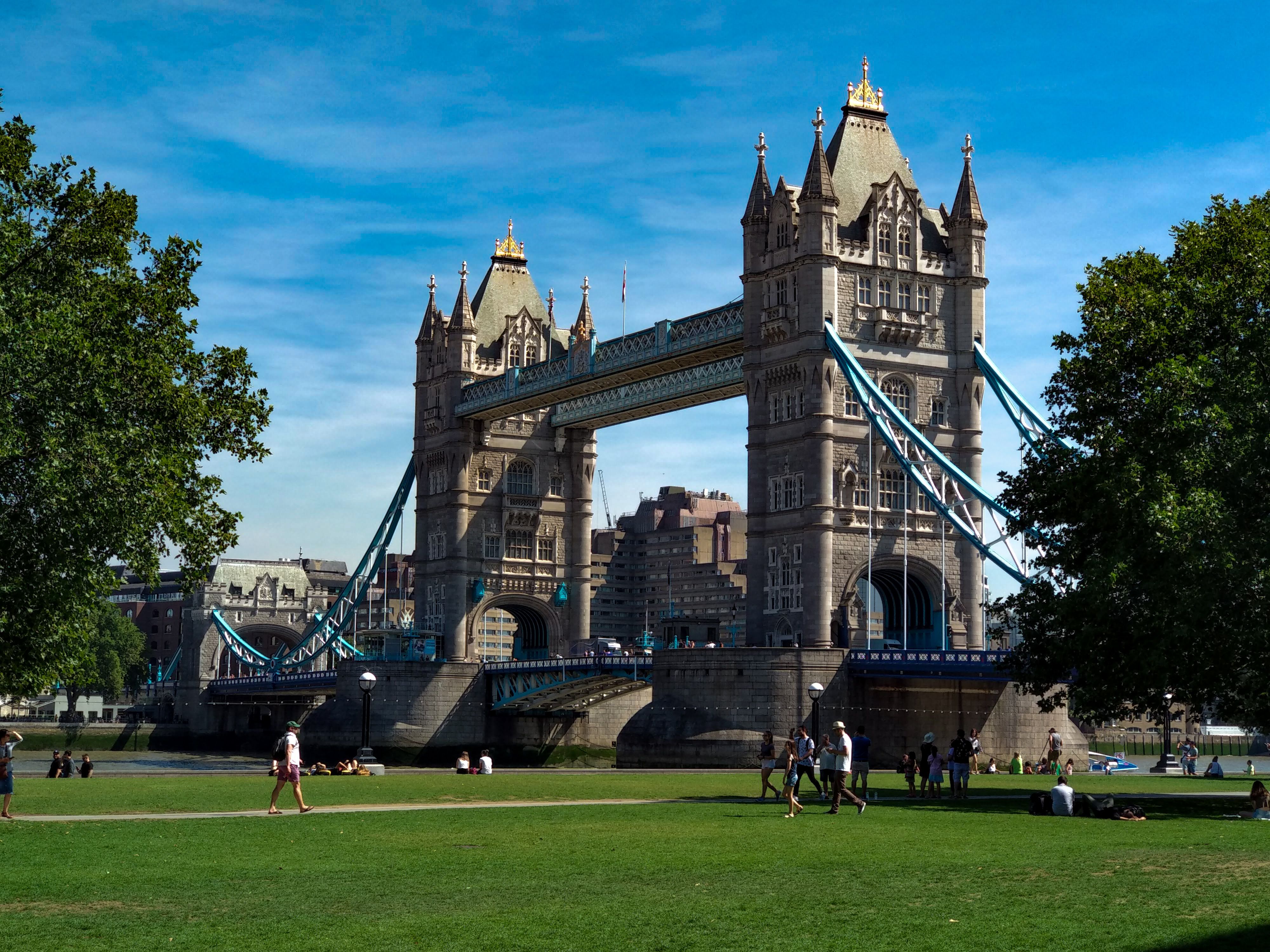 A beautiful view of Tower Bridge in London with people enjoying the sunny day.