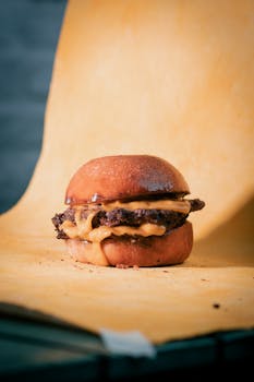 Close-up of a juicy cheeseburger with melted cheese on a rustic paper background.
