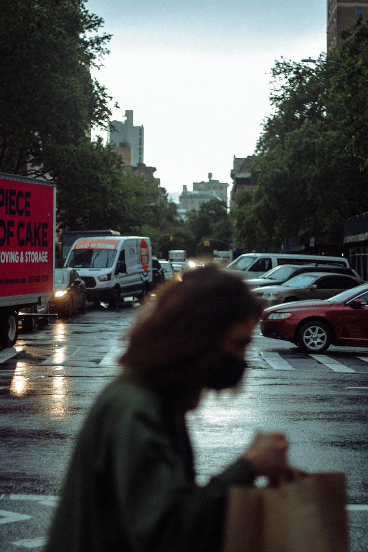 Man Crossing A Busy City Street Holding A Paper Bag 