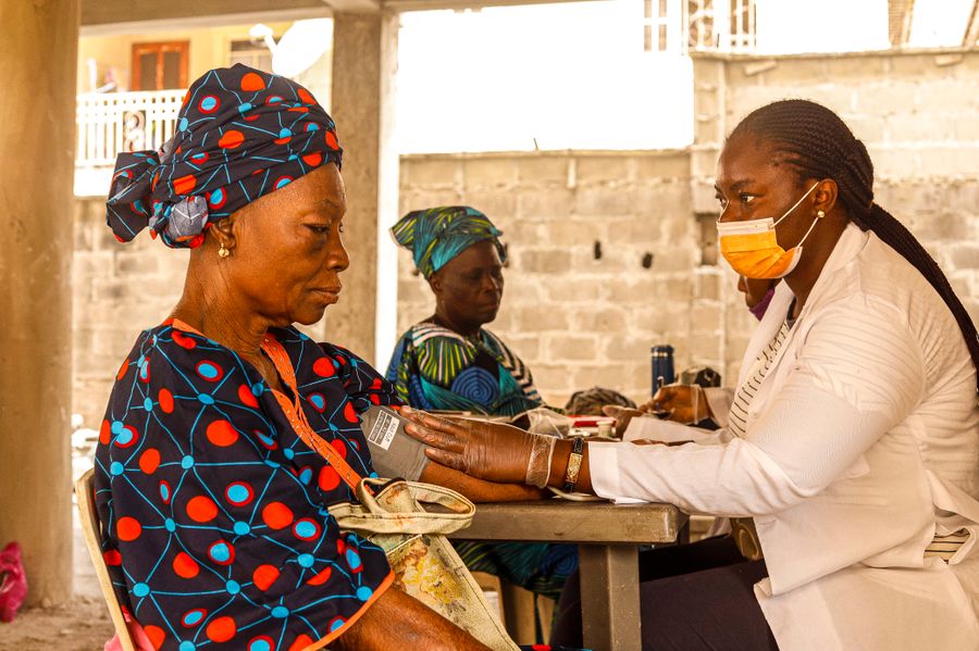 A nurse takes the blood pressure of an elderly woman during a home visit