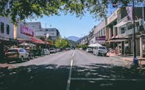 新西兰纳尔逊的街道宽阔，商店林立，汽车穿行，背景是连绵的山脉