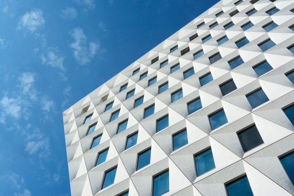Mavi gökyüzü önünde geometrik desenli çağdaş bina cephesi