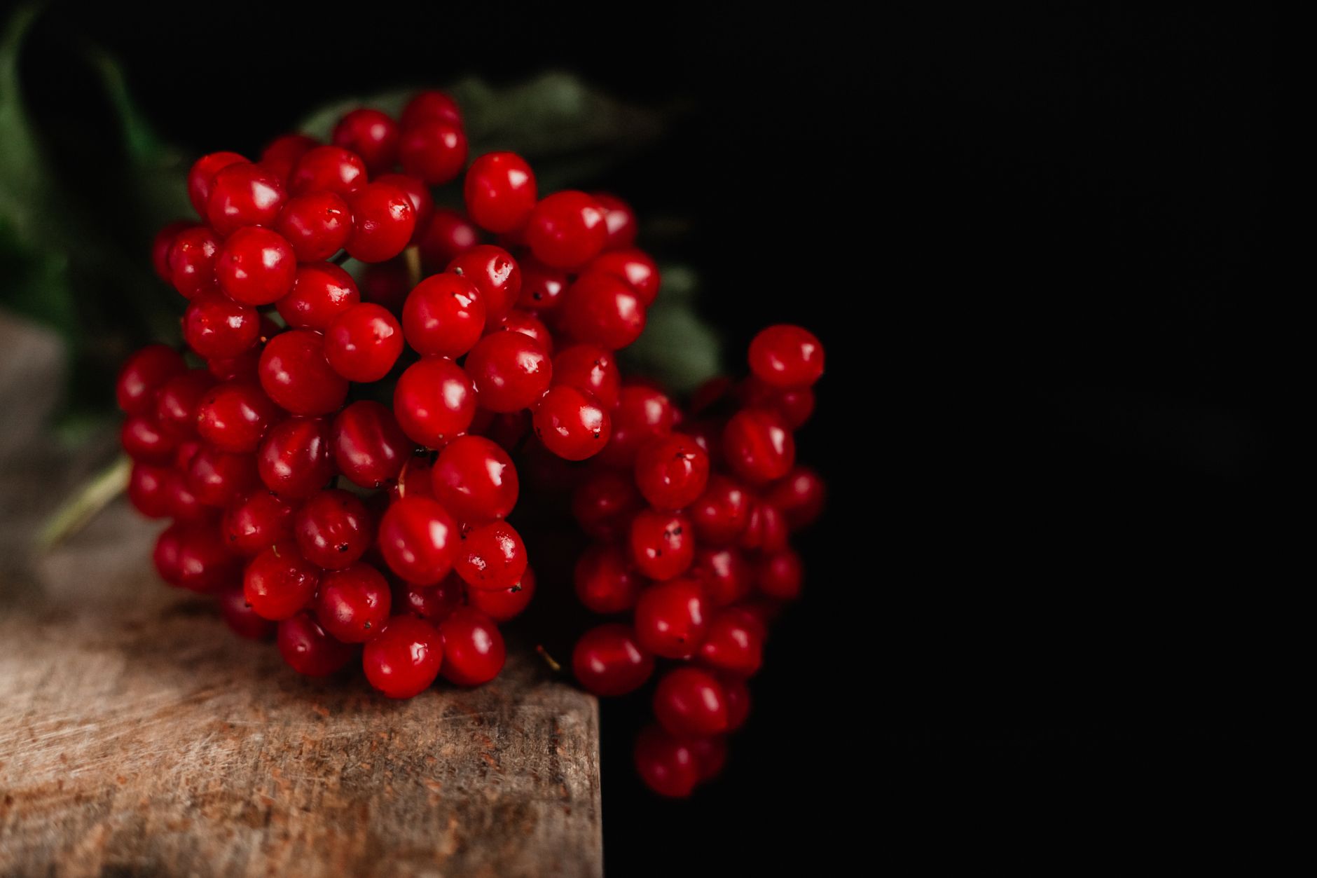Close-up of fresh red berries on a wooden surface with dark background, emphasizing natural colors.