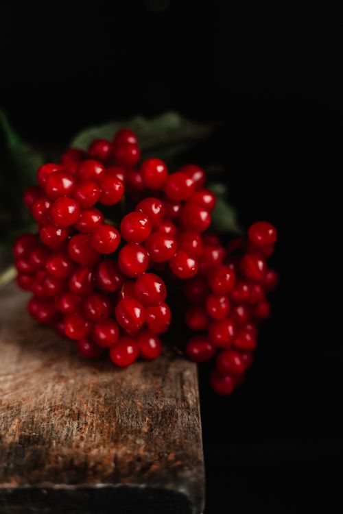 Free A close-up of fresh, red berries on a wooden surface against a dark background. Stock Photo