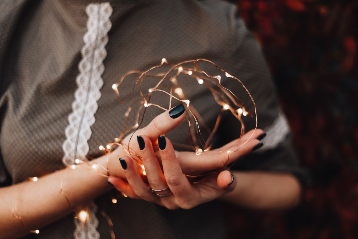 Close-up of woman holding glowing fairy lights, evoking a warm and cozy atmosphere.