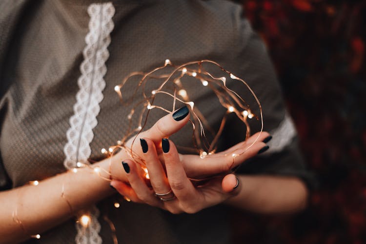 Close-up Of Woman With Her Hand And Arm Wrapped In Fairy Lights 