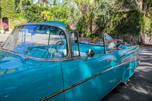 Close-up of a blue vintage convertible car parked outdoors in sunlight, showcasing classic design elements.