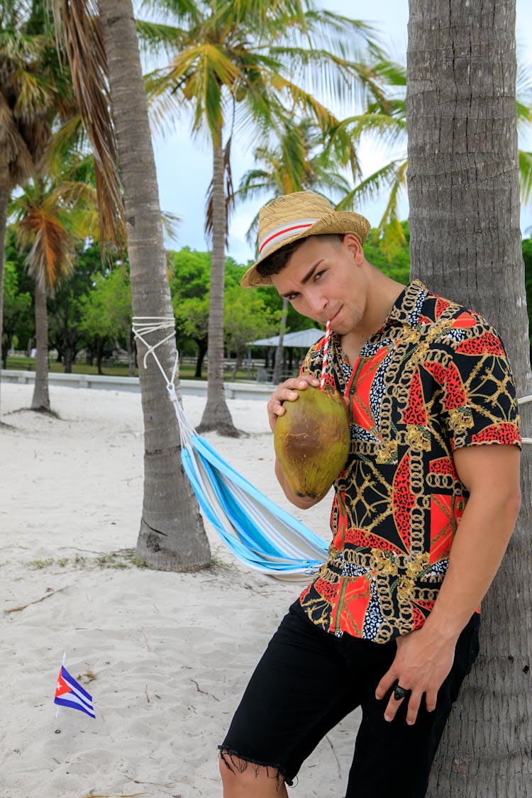 A Man With A Hat Drinking Coconut Juice