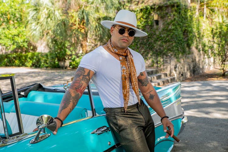 A Man With A Cigar Posing Beside A Blue Car