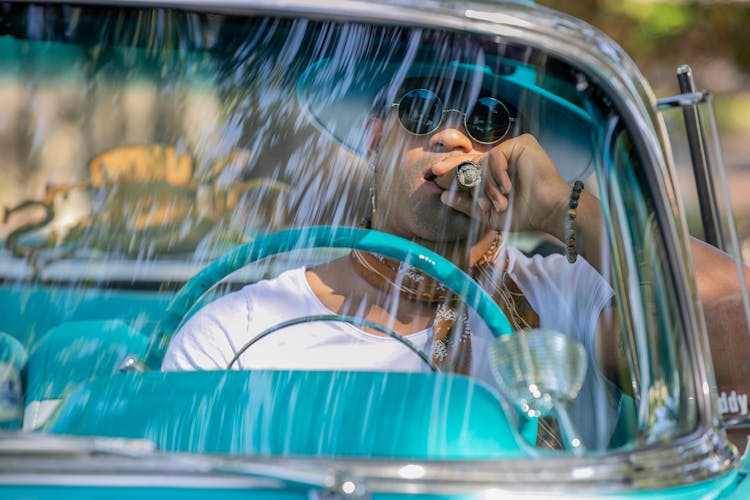 A Man Smoking A Cigar While In A Car 