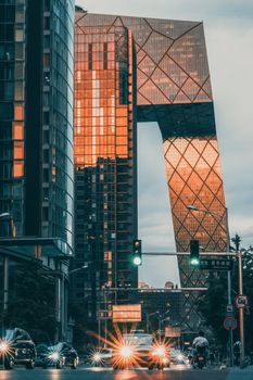 Stunning view of the CCTV Headquarters in Beijing with urban traffic and glowing city lights at dusk.