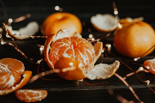 Free Close-up of a peeled tangerine surrounded by fairy lights, creating a warm, festive atmosphere. Stock Photo