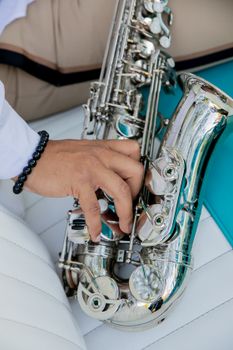 Detailed shot of a hand playing a shiny silver saxophone, emphasizing musical expression.