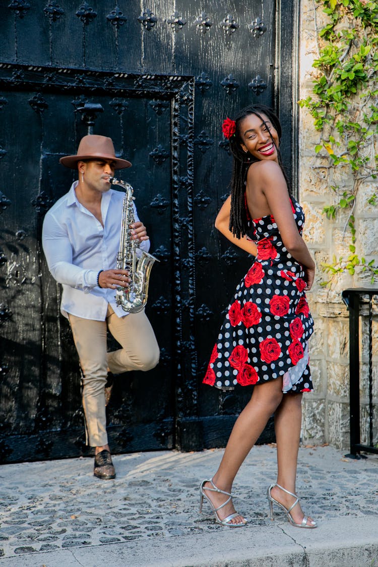 A Man Playing Saxophone While Woman Dancing