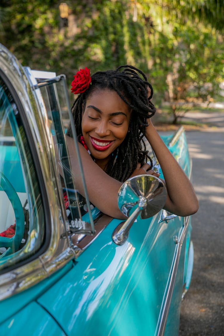 A Woman Touching Her Hair While Sitting In A Blue Car