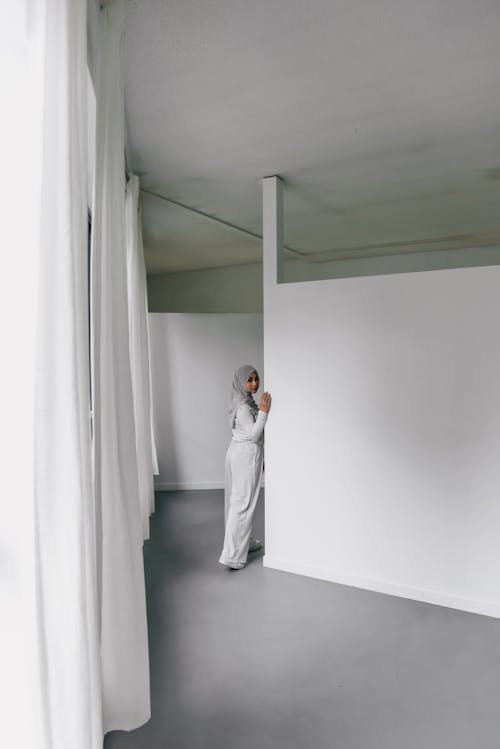 Woman Standing in Room Filled with White Curtains