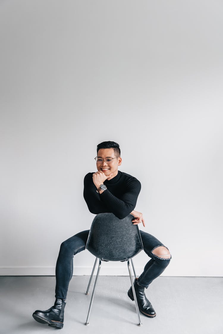 A Man Sitting On A Backward Chair 