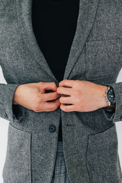 Free A person in a grey blazer buttoning up the jacket with a focus on hands. Stock Photo