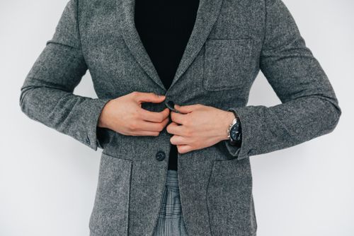 Free Person in grey business attire buttoning jacket, showcasing fashion style. Stock Photo