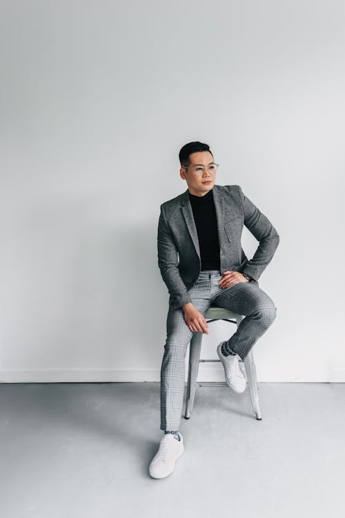 A Man in Gray Suit and Gray Pants Sitting on a Chair and Posing