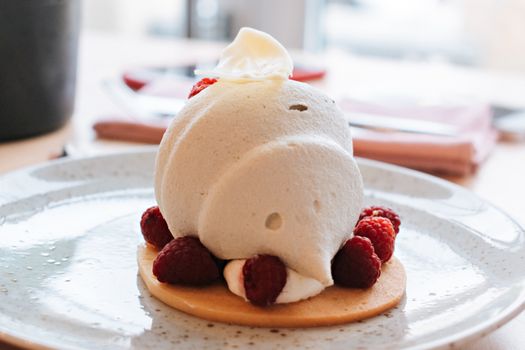 Delicious raspberry mousse cake garnished with fresh raspberries and cream, perfect for dessert lovers.