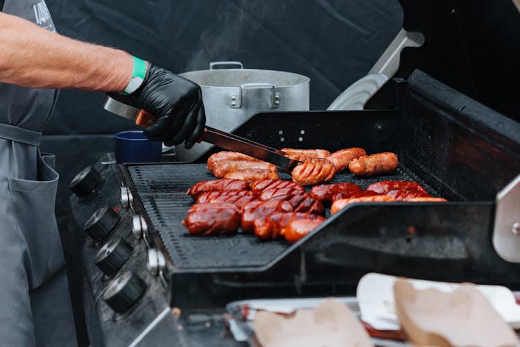 A Person Grilling A Sausage