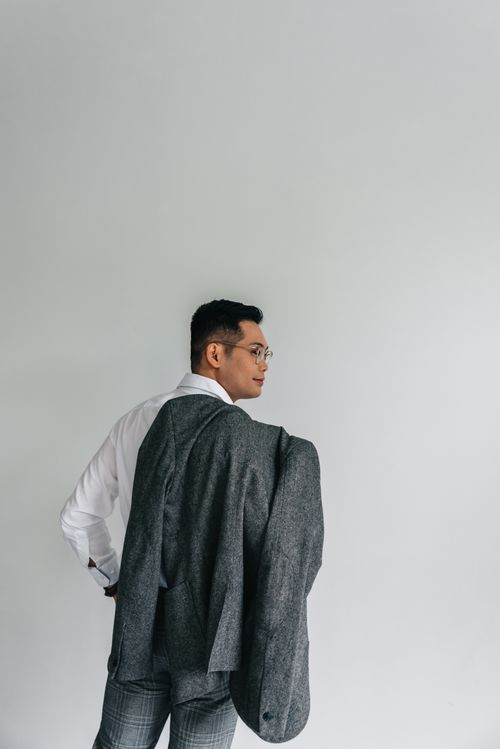 Free Confident man in a gray suit and white shirt posing against a minimalistic background. Stock Photo