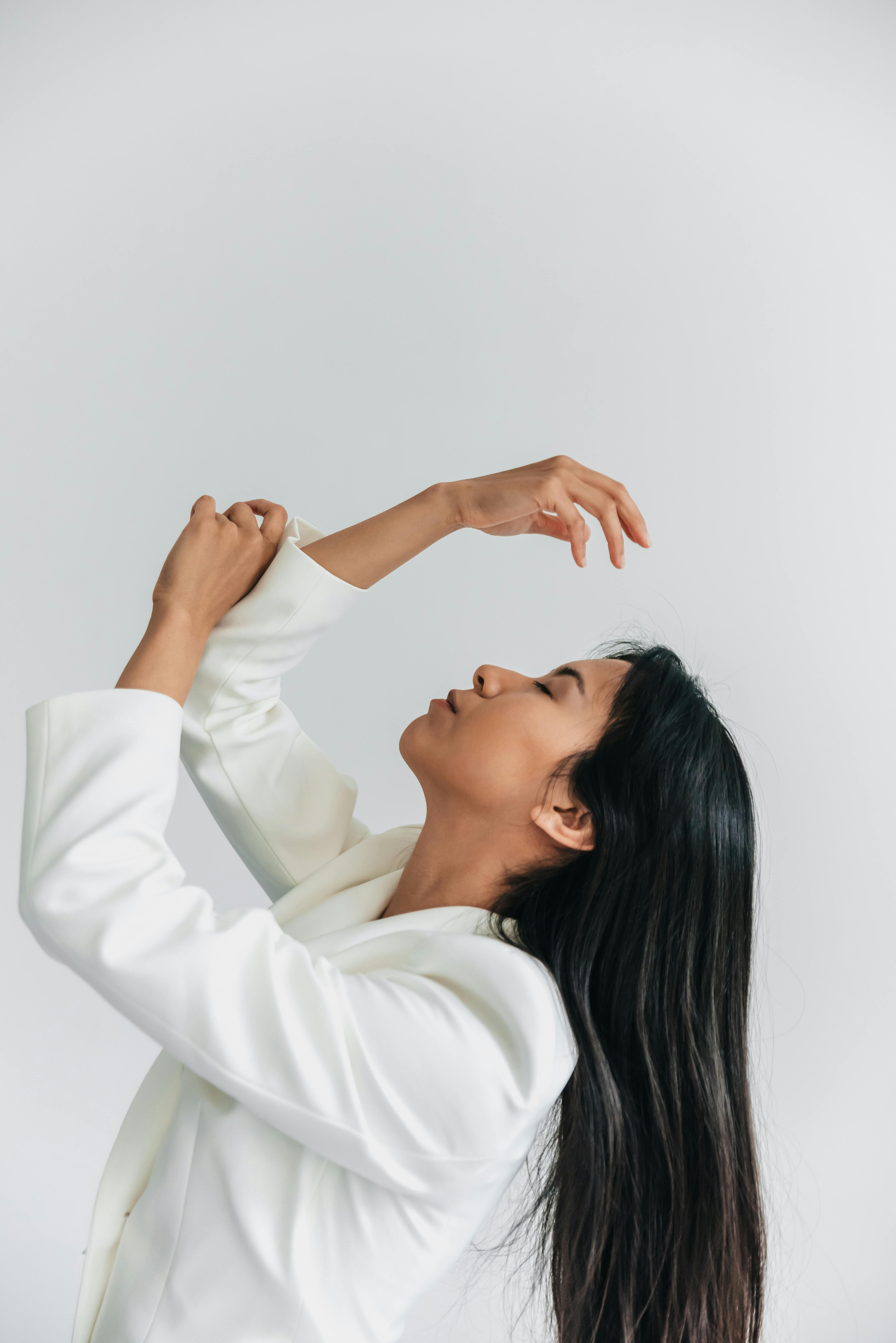 Profile portrait of an elegant woman with long hair posing gracefully on a white background.