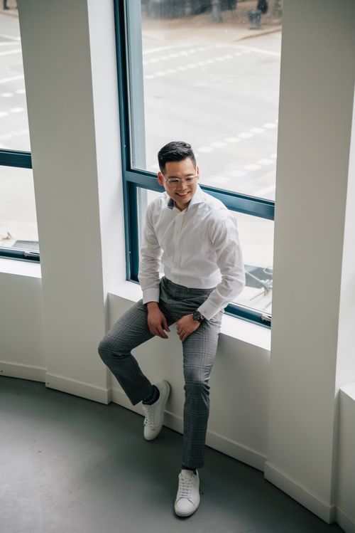 Free View of a confident businessman sitting on windowsill in modern office environment. Stock Photo