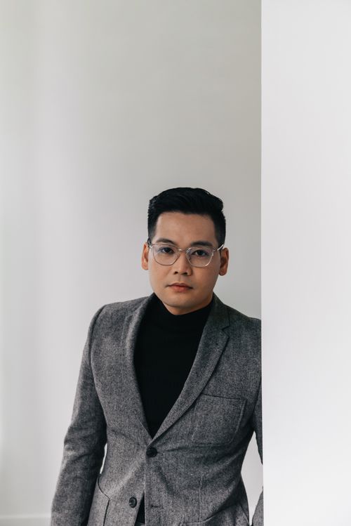 Free Young businessman wearing eyeglasses and a grey suit indoors, exuding confidence. Stock Photo