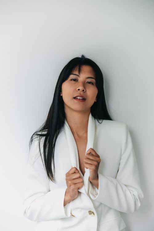 Free Sophisticated portrait of an Asian woman in a white blazer against a white background, exuding elegance. Stock Photo