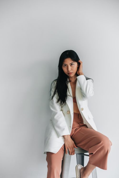 Free Stylish woman in a white blazer and beige pants posing indoors, exuding elegance and confidence. Stock Photo