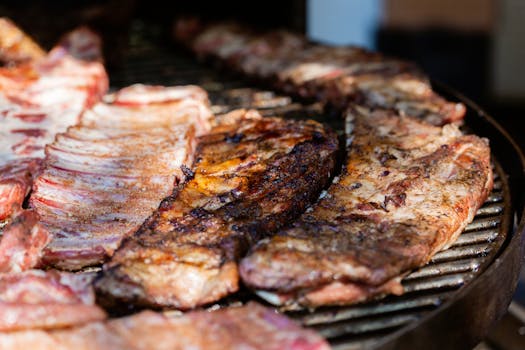 Juicy grilled ribs sizzling on an outdoor barbecue grill. Perfect for summer cookouts.