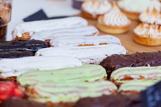 Close-up view of various flavored eclairs and pastries, perfect for dessert and bakery themes.