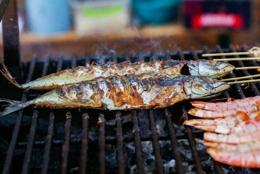 Close-up of grilled fish and shrimp cooking on an outdoor barbecue, showcasing delicious seafood options.