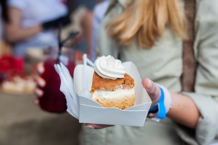 A Person Holding A Slice Of Cake In A Small Box