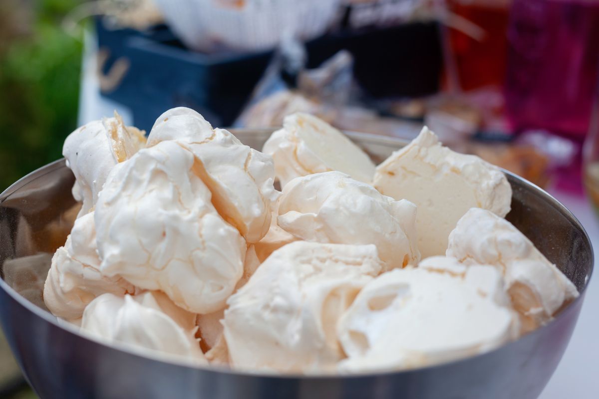 Delicious meringues piled in a metal bowl, perfect for dessert or a sweet treat.