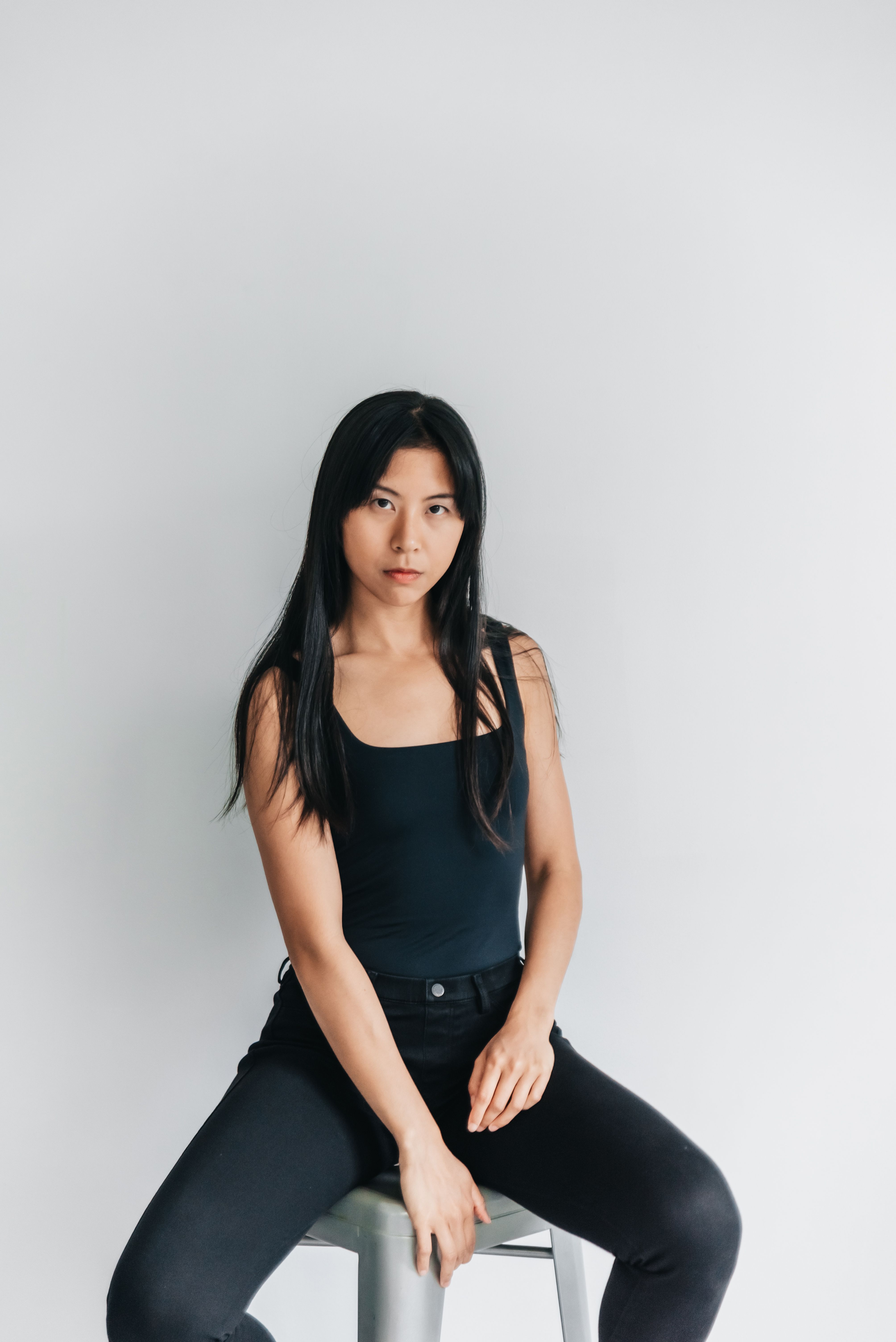A stylish woman poses confidently in a minimalist studio environment, showcasing fashion and elegance.