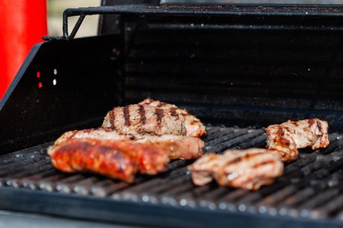 Free Tantalizing grilled steak and sausages sizzling on an outdoor barbecue grill, perfect for summer picnics. Stock Photo