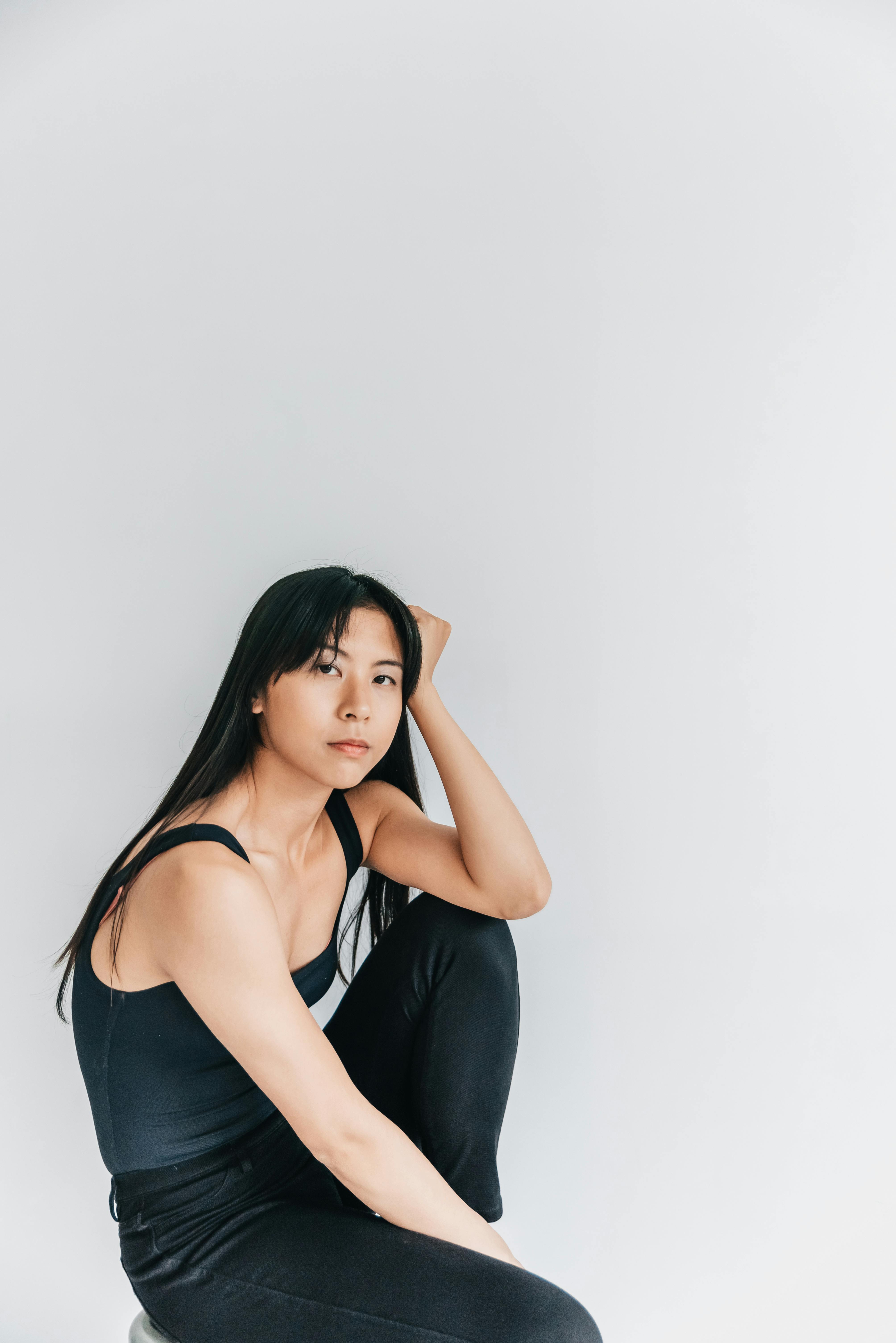 一位亚洲女性在极简主义环境中摆姿势的优雅肖像，展示时尚和风格