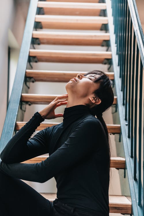 A Woman in Black Long Sleeves Sitting on the Stairs