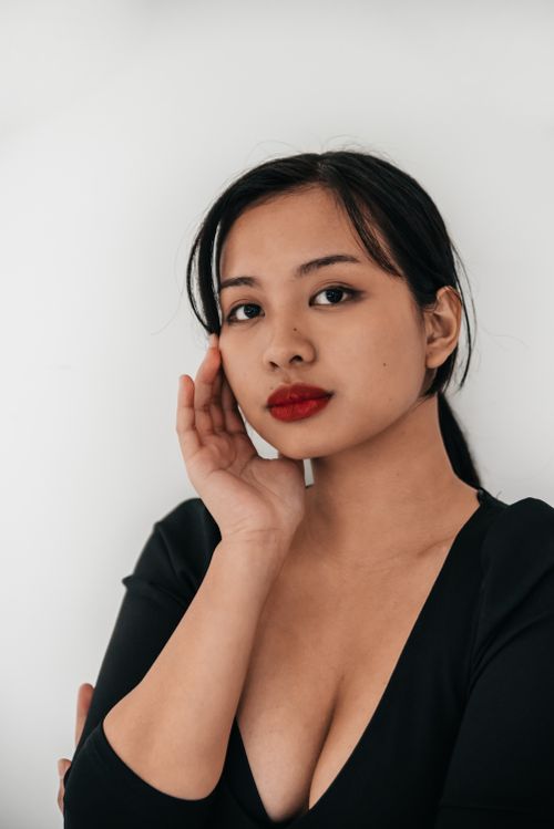 Free Stunning portrait of an Asian woman in a black top, elegantly posing with a thoughtful expression. Stock Photo