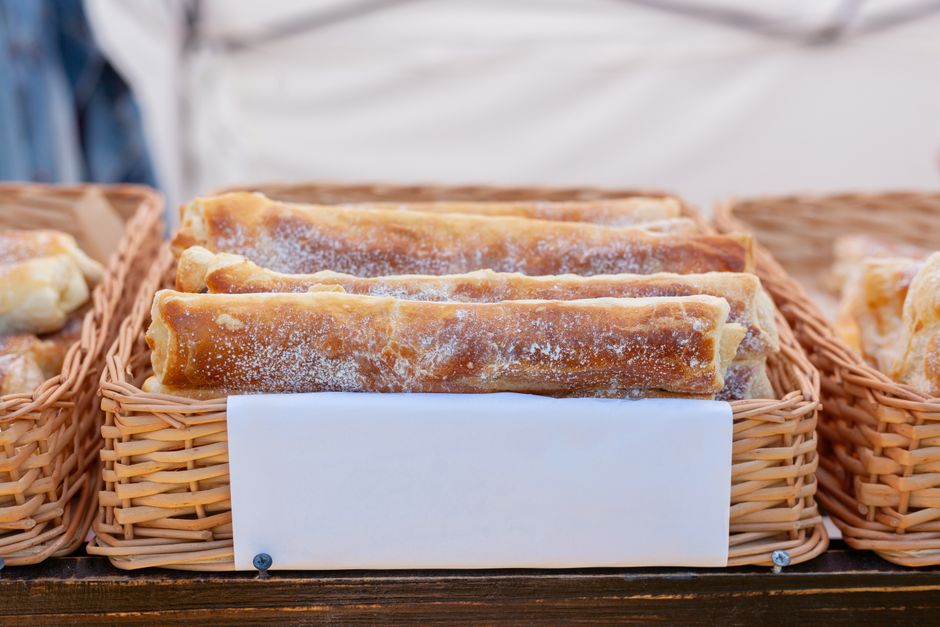A golden, flaky slice of freshly baked banitsa, a traditional Bulgarian pastry, on a plate.