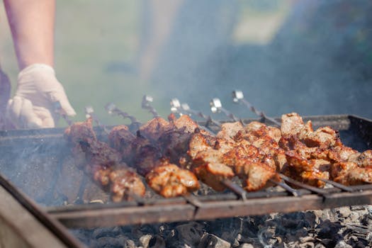 Close-up of delicious grilled meat skewers sizzling on a smoky barbecue outdoors.
