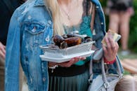 Person in Denim Jacket Carrying a Foil Pan with Mussels
