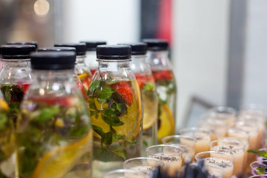 Close-up of plastic bottles with fruit-infused water and herbs, perfect for a refreshing drink.