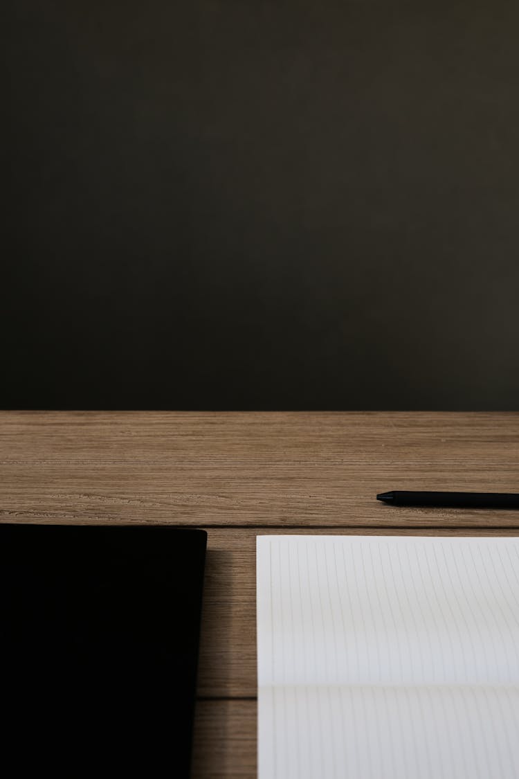 A Pen And White Paper On Brown Wooden Table