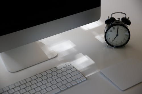 Photo of a Keyboard Near an Alarm Clock