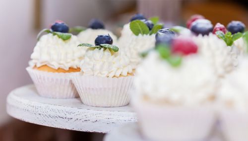 Free Close-up of cupcakes topped with blueberries, raspberries, and creamy frosting, ideal for dessert and baking themes. Stock Photo